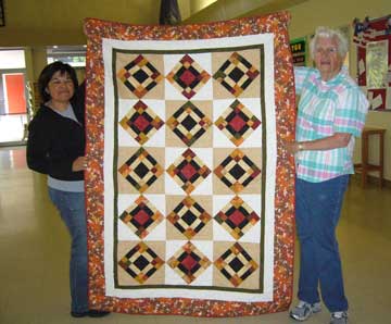 Staff accept quilt donated by SRQG.